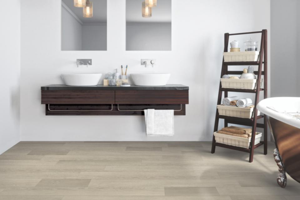 warm toned luxury vinyl flooring in bathroom with claw foot tub, sink, and storage rack.